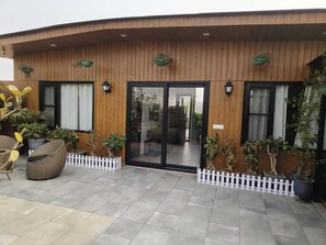 A modern building with a wooden facade, large glass doors, and potted plants. - vandanas bed and breakfast (New Delhi)