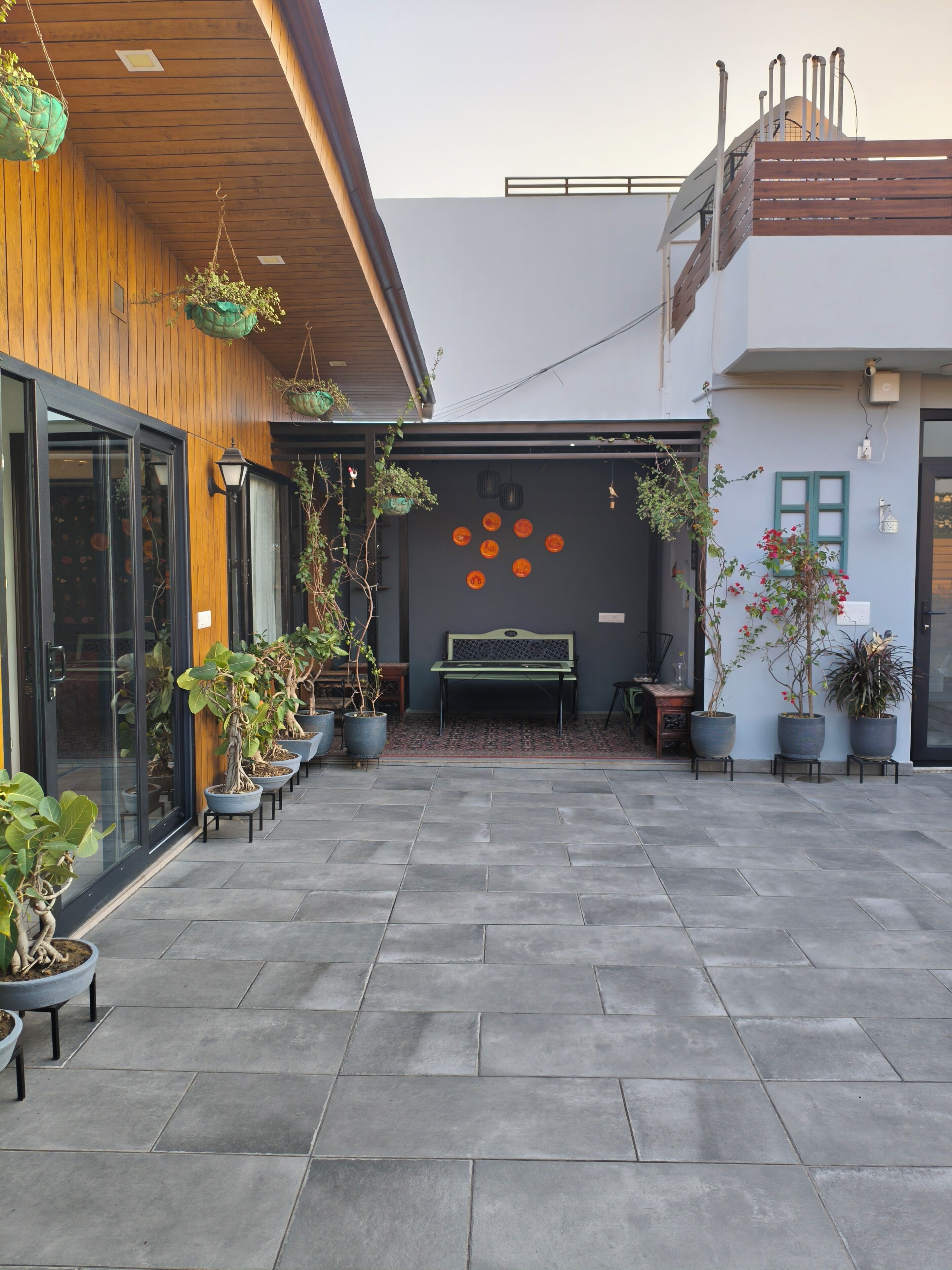 Un patio con plantas en macetas, un banco y una pared con adornos circulares.