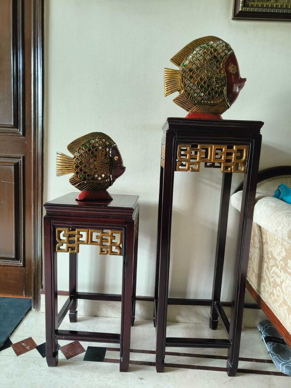 Two wooden tables with intricate designs, one with a fish-shaped top and the other with a geometric pattern.