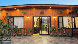 A building with a wooden facade, large windows, and potted plants. - vandanas bed and breakfast (New Delhi)