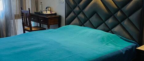 A bedroom with a bed, a nightstand, a chair, and a desk. There are three framed pictures on the wall.