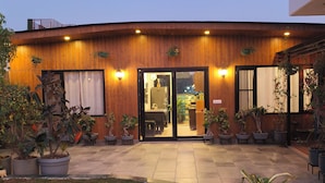 A modern building with a wooden facade, large glass doors, and potted plants in the courtyard. - vandanas bed and breakfast (New Delhi)