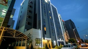 Un moderno edificio de hotel con un letrero llamativo, varios pisos y una entrada bien iluminada.