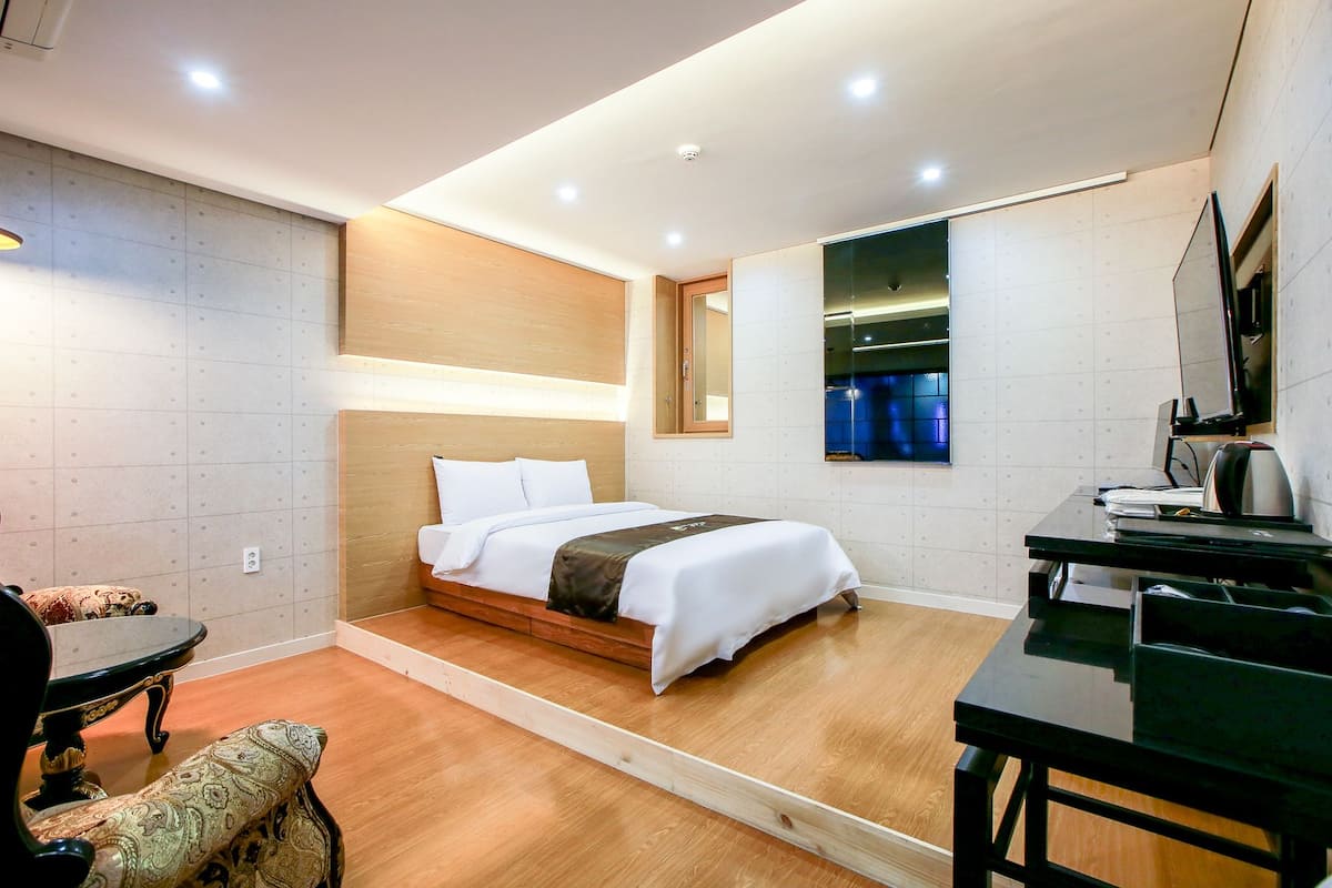A hotel room with a bed, a desk, a chair, and a small table.