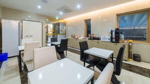 Una habitación de hotel moderna con zona de comedor, cocina equipada con microondas y un amplio ventanal.