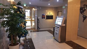 Un vestíbulo de hotel con una recepción, un quiosco de información digital y un árbol de Navidad.