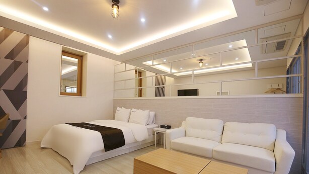 Una habitación de hotel moderna con cama, sofá, una mesita de café y estanterías empotradas.