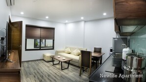 Een ruimtelijk ingerichte leefruimte met een kitchenette, een bank, een salontafel en een eettafel.