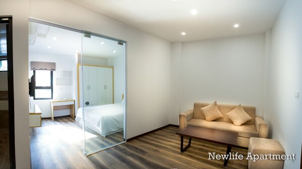 Un apartamento moderno con un armario de vidrio, una cama, un sofá y una mesita.