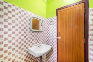A bathroom with a checkered tile wall, a wooden door, and a white sink.