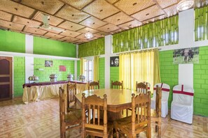 A dining area with a wooden table and chairs, green walls, and bamboo curtains.