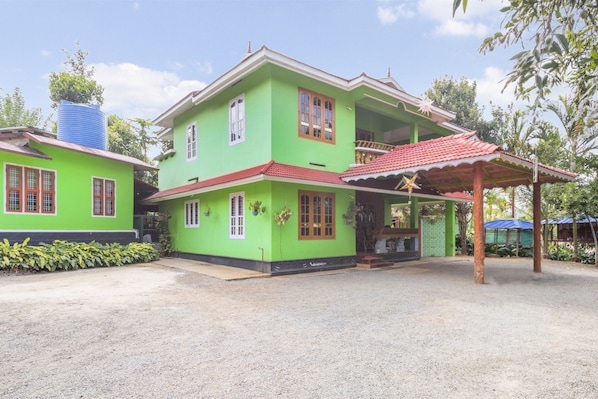 A two-story house with a green exterior and a red roof.