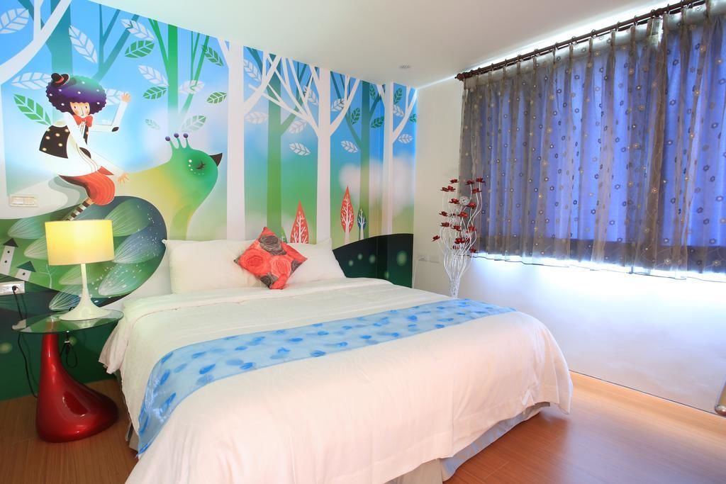 A bedroom with a bed, a nightstand, a lamp, and a window with curtains.