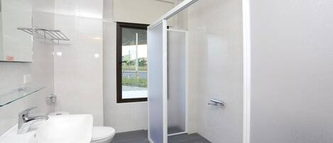 A modern bathroom with a toilet, sink, and shower area.