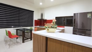 A modern kitchen with a central island, a dining area with colorful chairs, and a large refrigerator. - Dania Garden (Luodong)