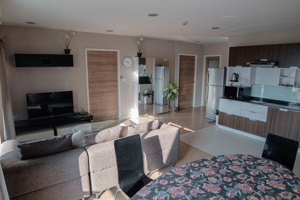 A modern living room with a sofa, TV, and a dining area with a patterned tablecloth.