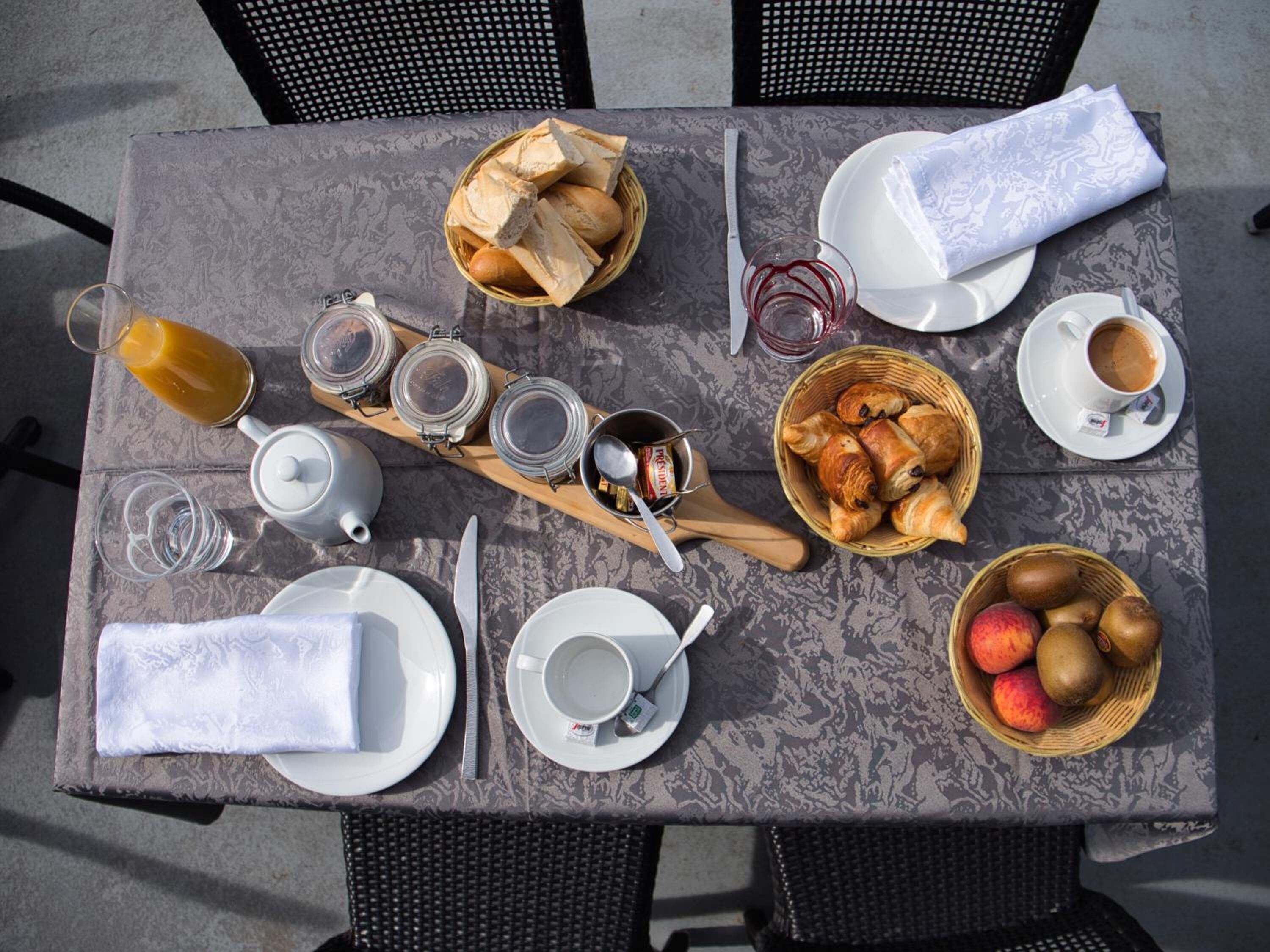 Ett dukat bord för frukost med bröd, bakverk, frukt och drycker.