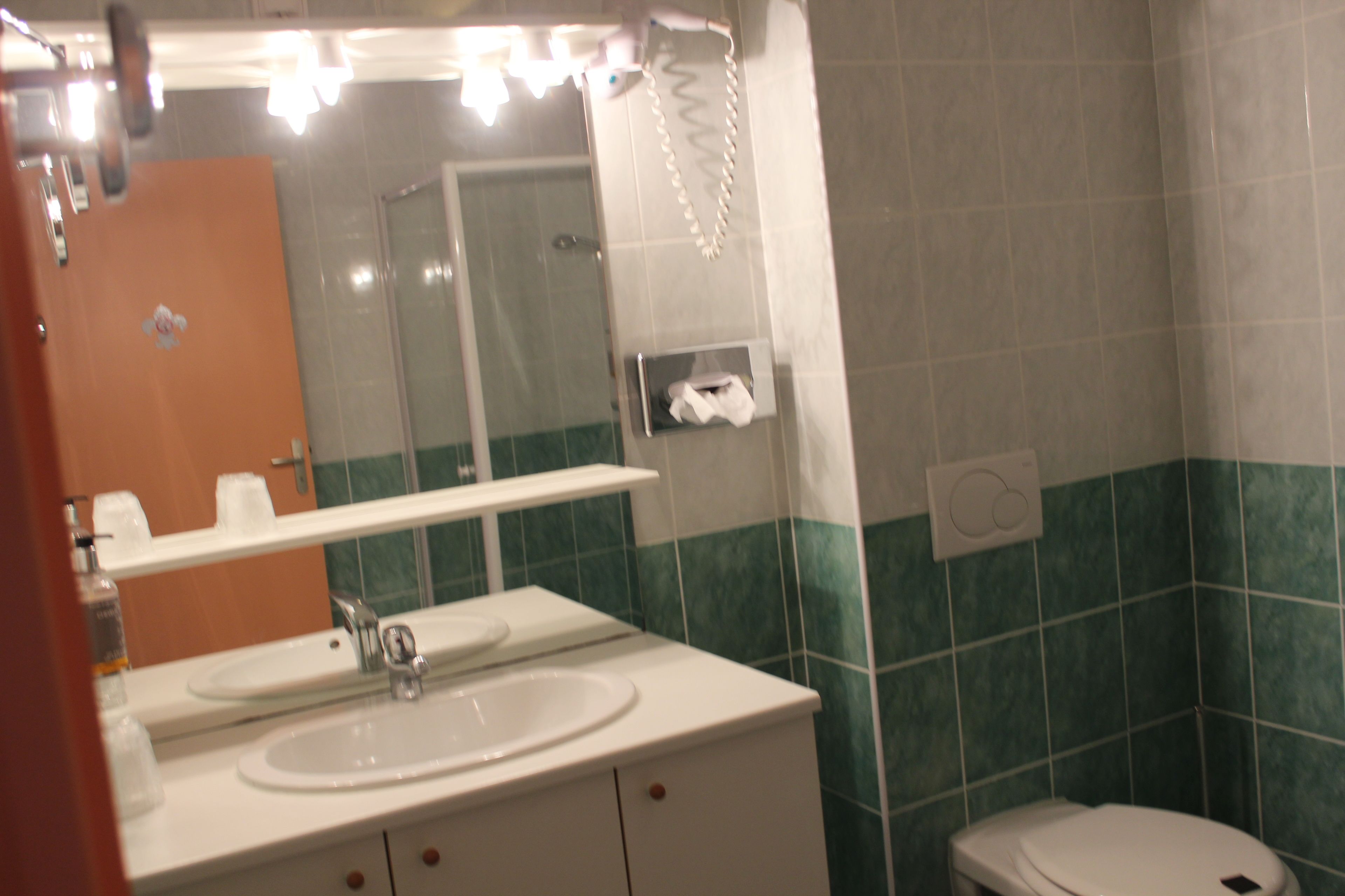 A bathroom with a white sink, mirror, and a toilet.