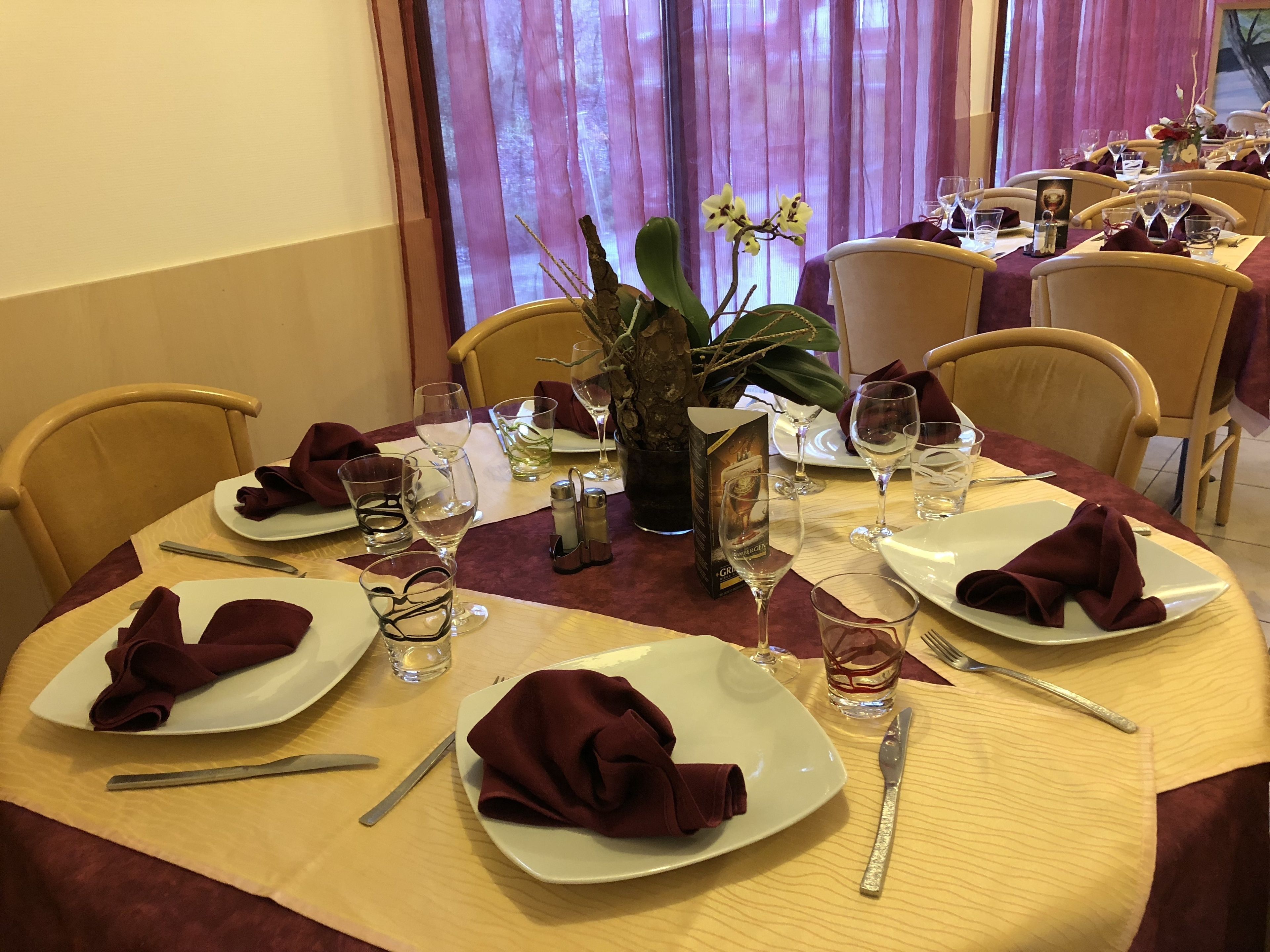 Een eettafel gedekt voor vier personen, met borden, bestek en wijnglazen.