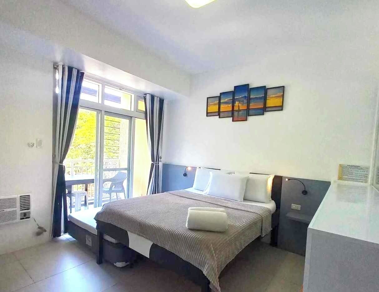 Un dormitorio moderno con una cama grande, un escritorio y un balcón con mobiliario exterior.