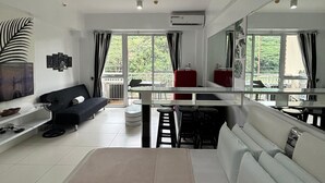 Een moderne hotelkamer met een groot bed, een bank, een eettafel en een balkon met uitzicht.