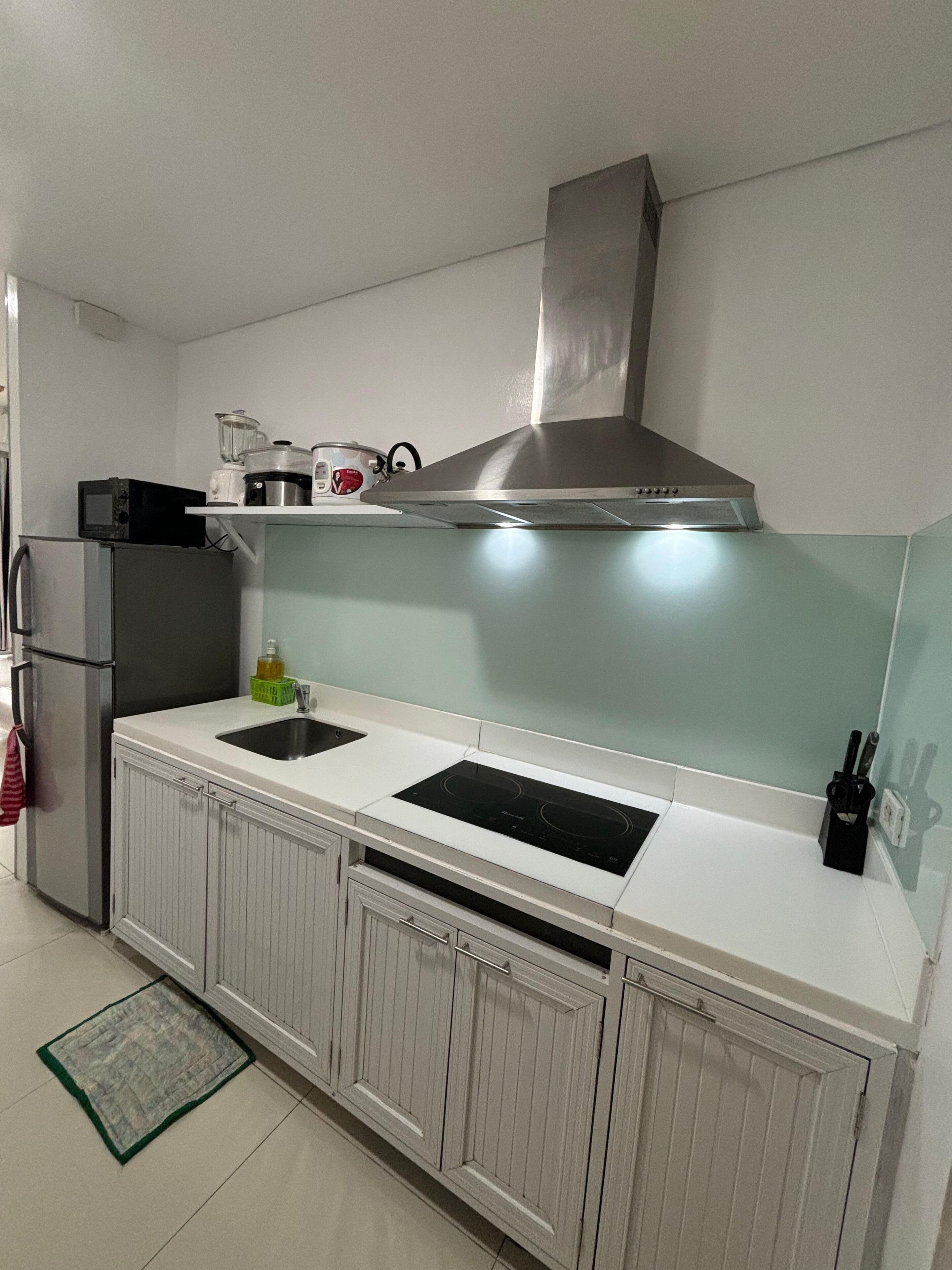 Una cocina moderna con campana de acero inoxidable, horno empotrado, microondas y lavamanos.