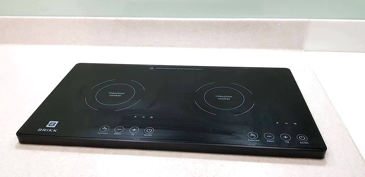 A black induction cooktop with two induction circles, a power button, and a temperature control knob.