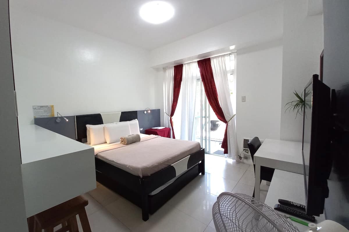 A modern hotel room with a bed, desk, chair, and a TV.
