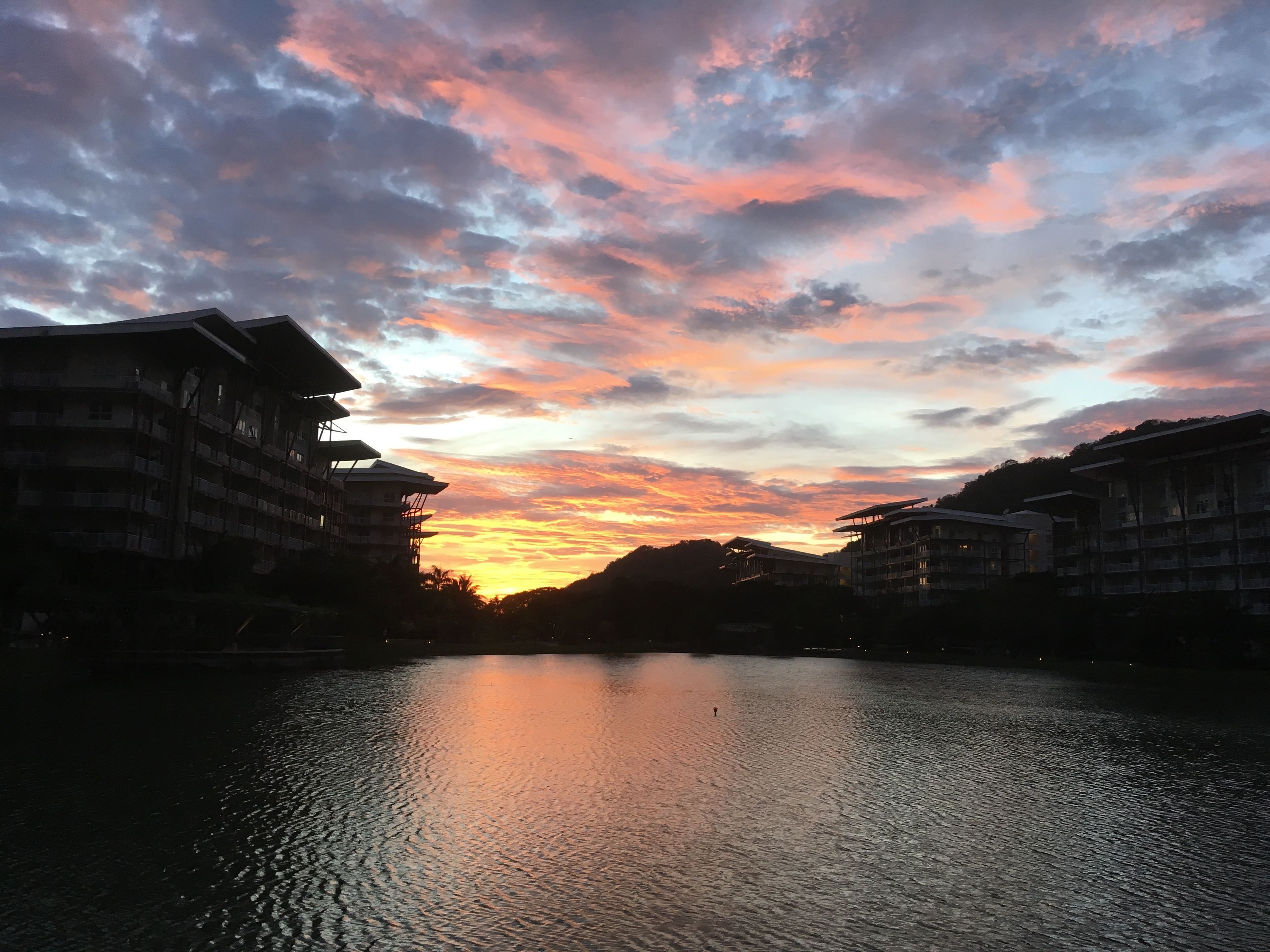 A sunset over a body of water with buildings on either side.