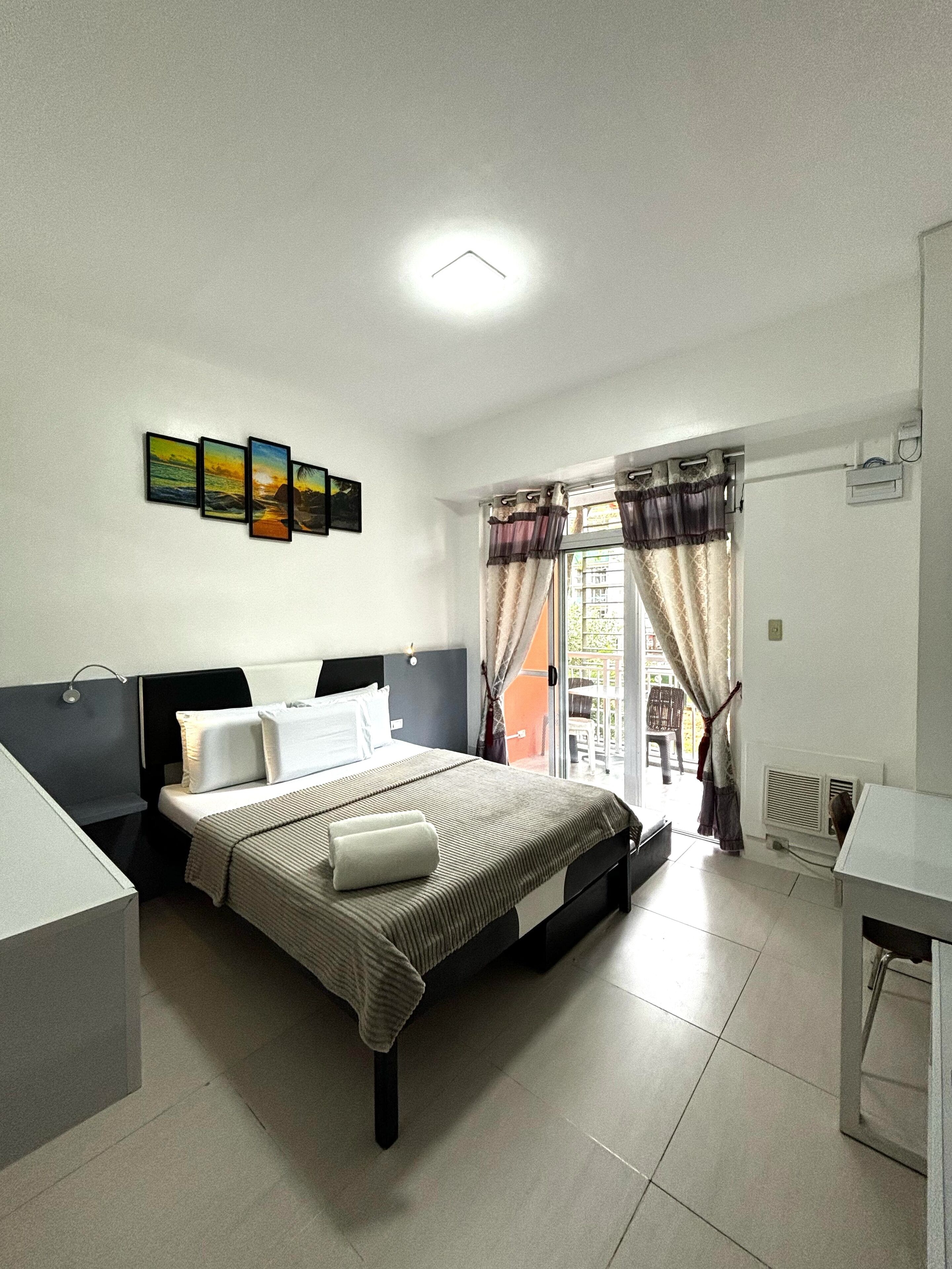 Une chambre à coucher comprenant un lit, une table de chevet, une fenêtre avec des rideaux et un climatiseur fixé au mur.