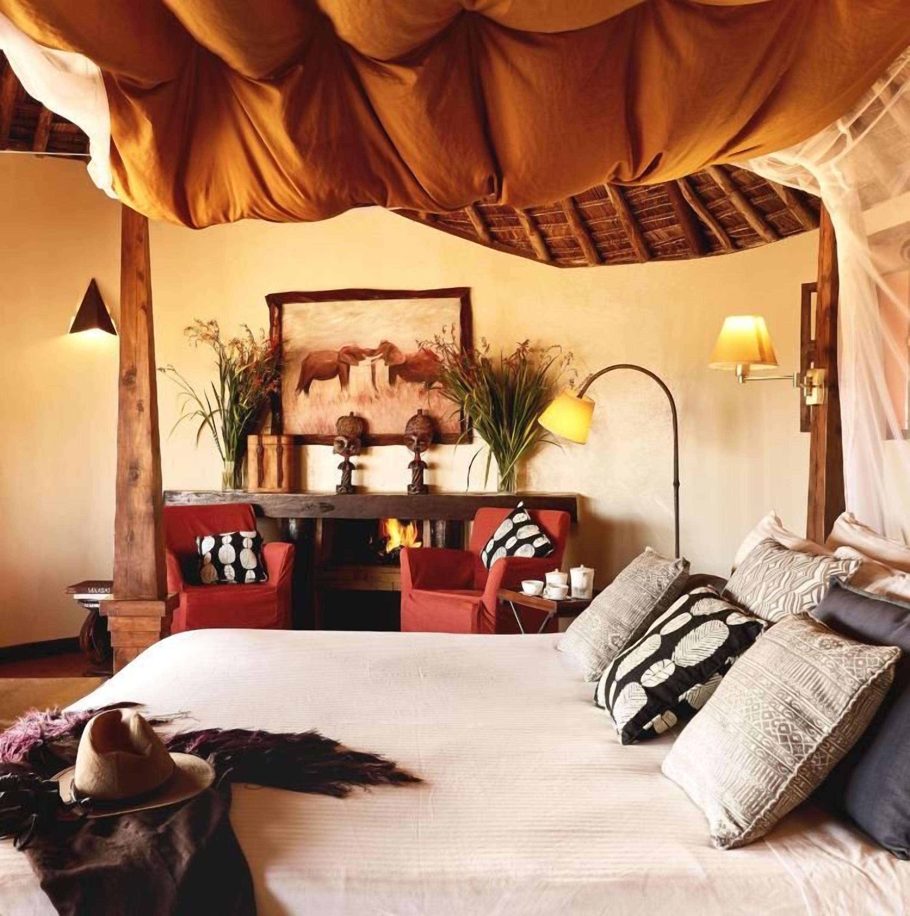 A room with a bed, a desk, chairs, and a painting on the wall.