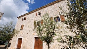A stone building with two wooden doors and windows, surrounded by olive trees. - Bed & Breakfast Korta Gira (Porec)