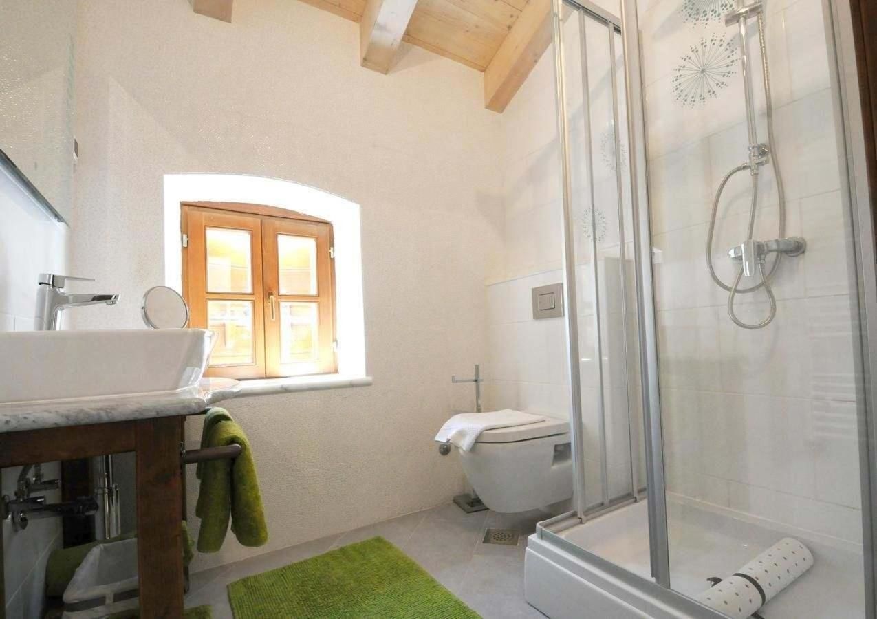 A bathroom with a sink, toilet, shower, and a window.
