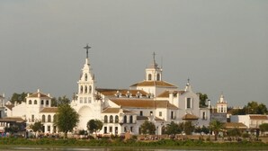Una iglesia blanca grande con un campanario y varios edificios más pequeños al frente.