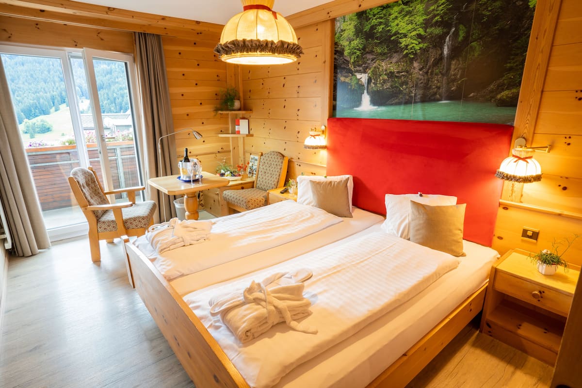 Une pièce en bois avec un lit, un bureau et une chaise. Il y a une fenêtre et un tableau représentant une cascade.