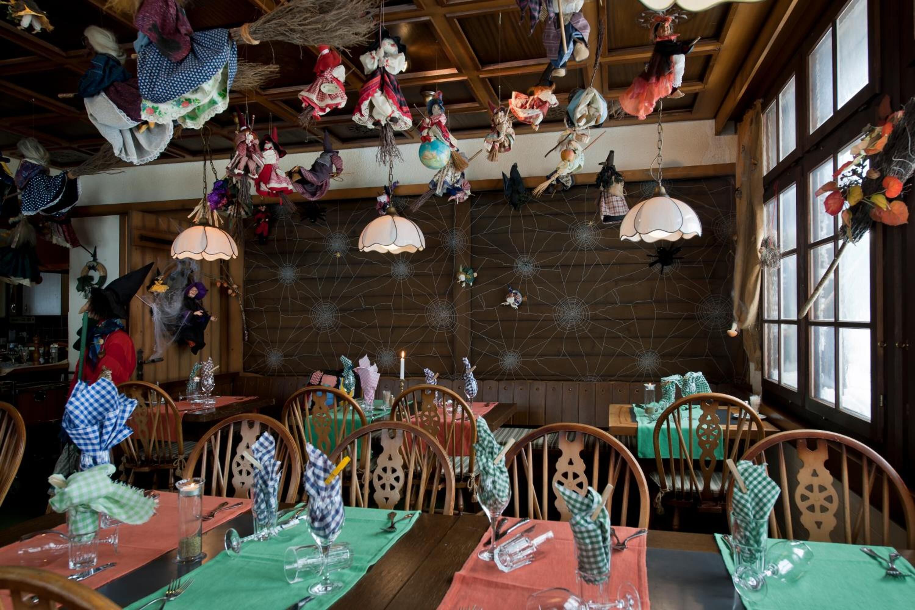 Un restaurant au décor intérieur en bois, agrémenté de décorations suspendues, et dont les tables sont dressées pour le service.