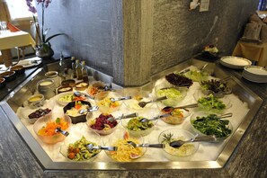 A buffet with various dishes including salads, vegetables, and pasta.