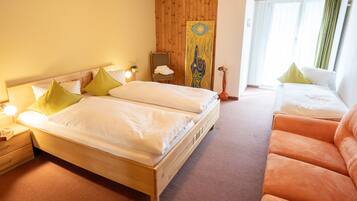 Une chambre d’hôtel avec un lit en bois, une table de chevet en bois, une chaise et un tableau au mur.