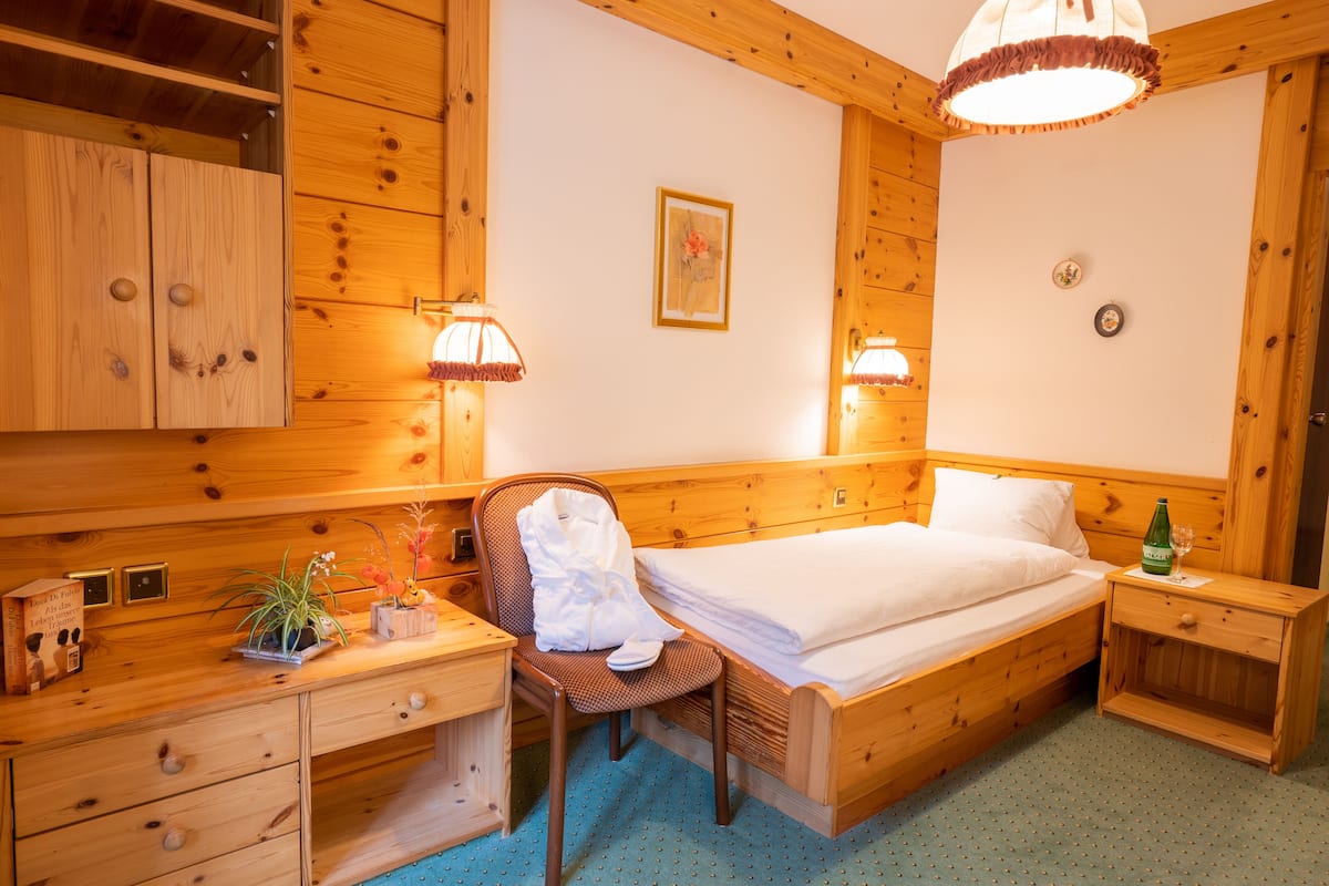 Une pièce en bois comprenant un lit, une chaise, une table de chevet et une commode.