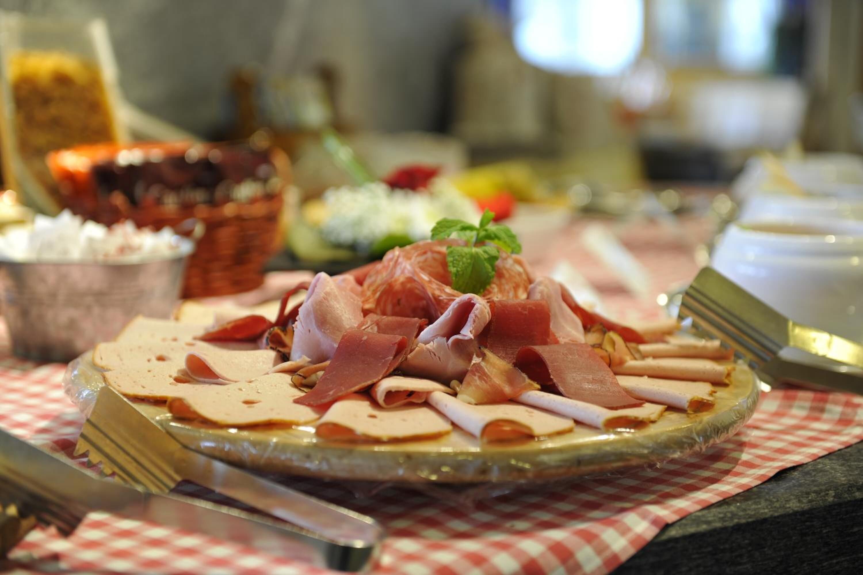 A plate of assorted meats on a checkered tablecloth.