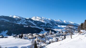 Un pueblo cubierto de nieve con edificios y una iglesia, rodeado de montañas.