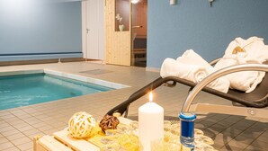 A poolside area with a lounge chair, towels, a candle, and a tray with decorative items. - Hotel Sonne (Wildhaus-Alt St. Johann)