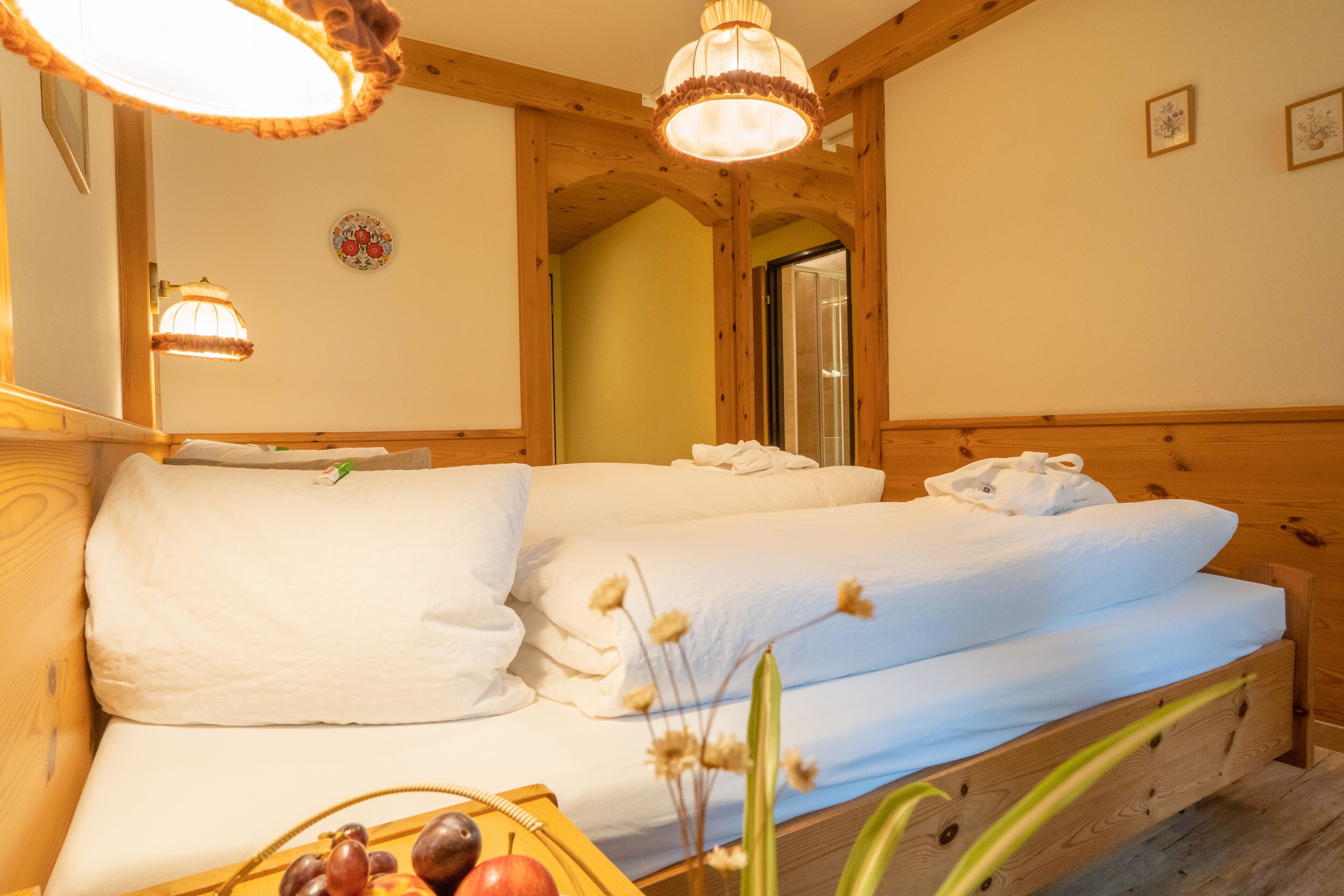 Een knus ingerichte kamer met een houten bed, een nachtkastje met fruit en een spiegel.