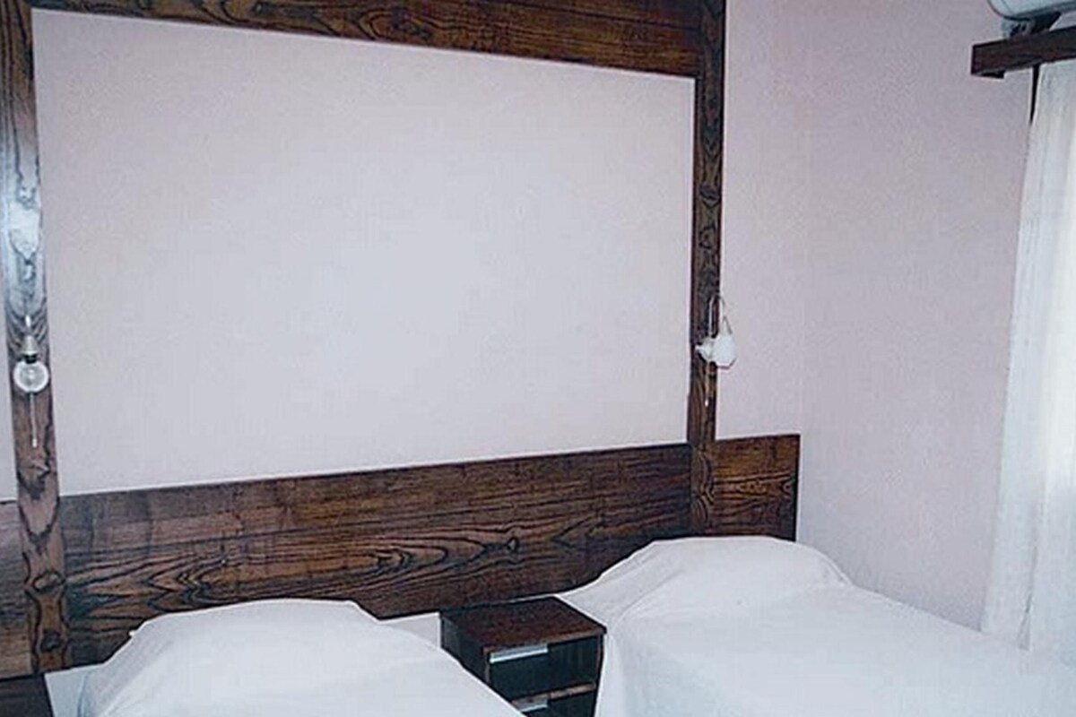 A simple, clean room with a wooden headboard, a single bed, and a small nightstand.