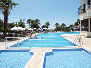 A swimming pool with clear blue water, surrounded by lounge chairs and umbrellas. - Area Hotel (Fethiye)
