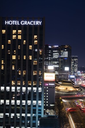 Un edificio de hotel moderno y alto, con ventanas iluminadas y un cartel llamativo que dice 'HOTEL GRACERY'.