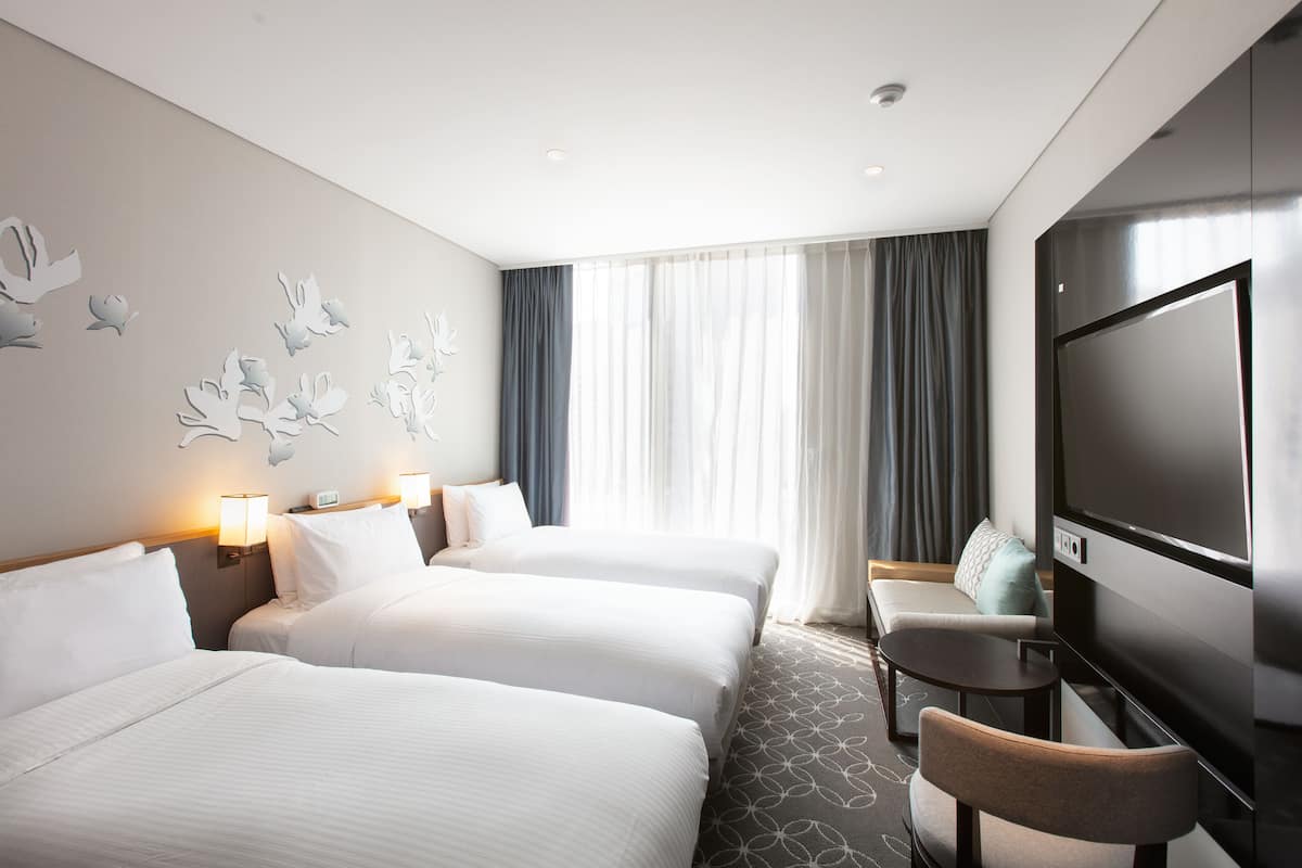 Une chambre d’hôtel avec deux lits, une télévision, une petite table et un canapé.