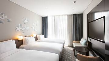 Une chambre d’hôtel avec deux lits, une télévision, une petite table et un canapé.