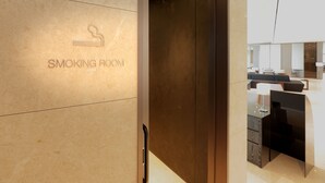 A modern interior with a sign for a smoking room, a wooden door, and contemporary furniture. - Hotel Gracery Seoul (Seoul)