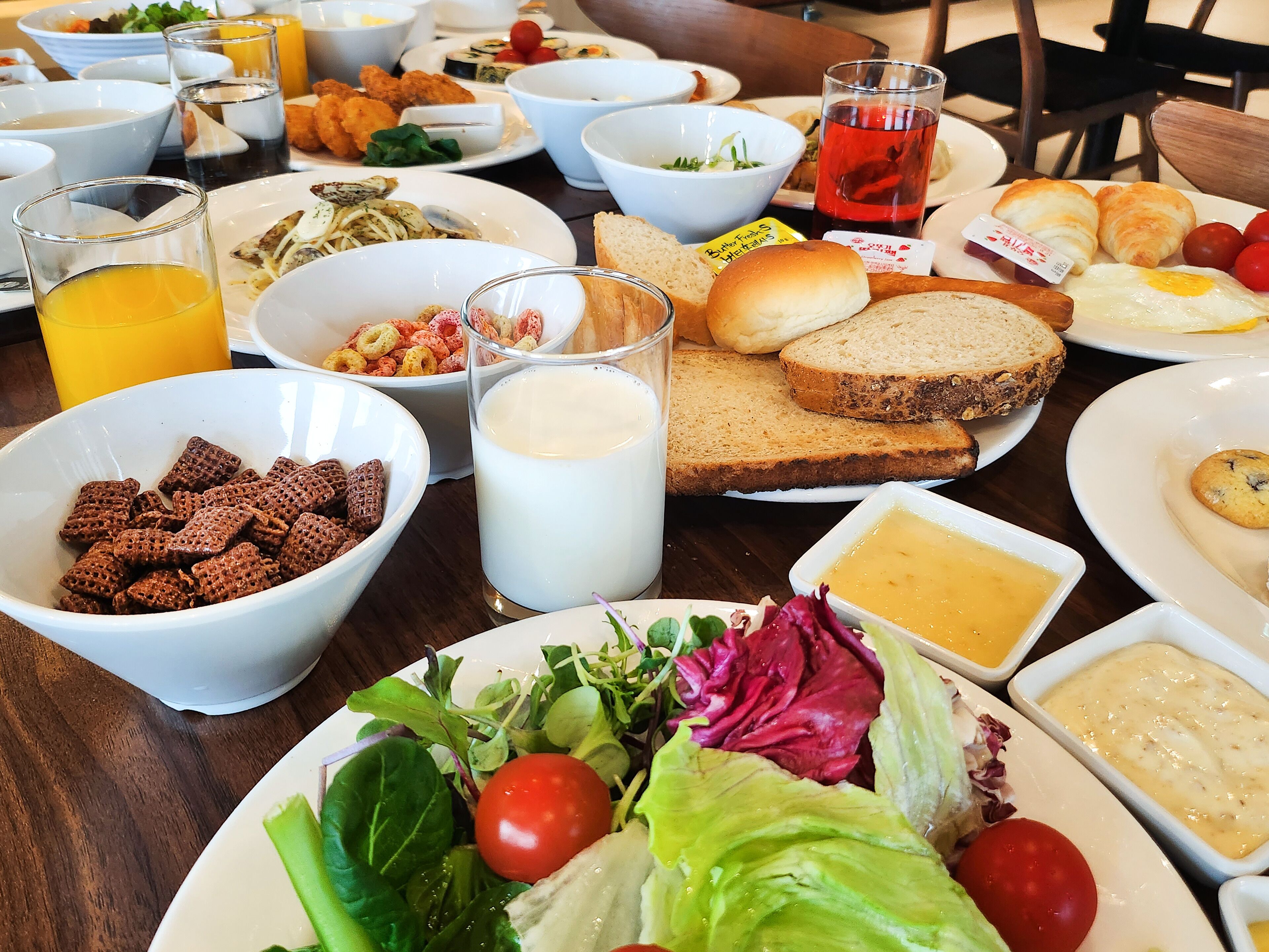 A table with various breakfast items including cereal, milk, bread, eggs, and a salad.